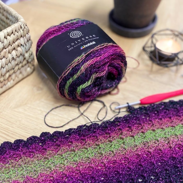 DIY crochet shawl patterns with purple and green yarn and knitting needles.