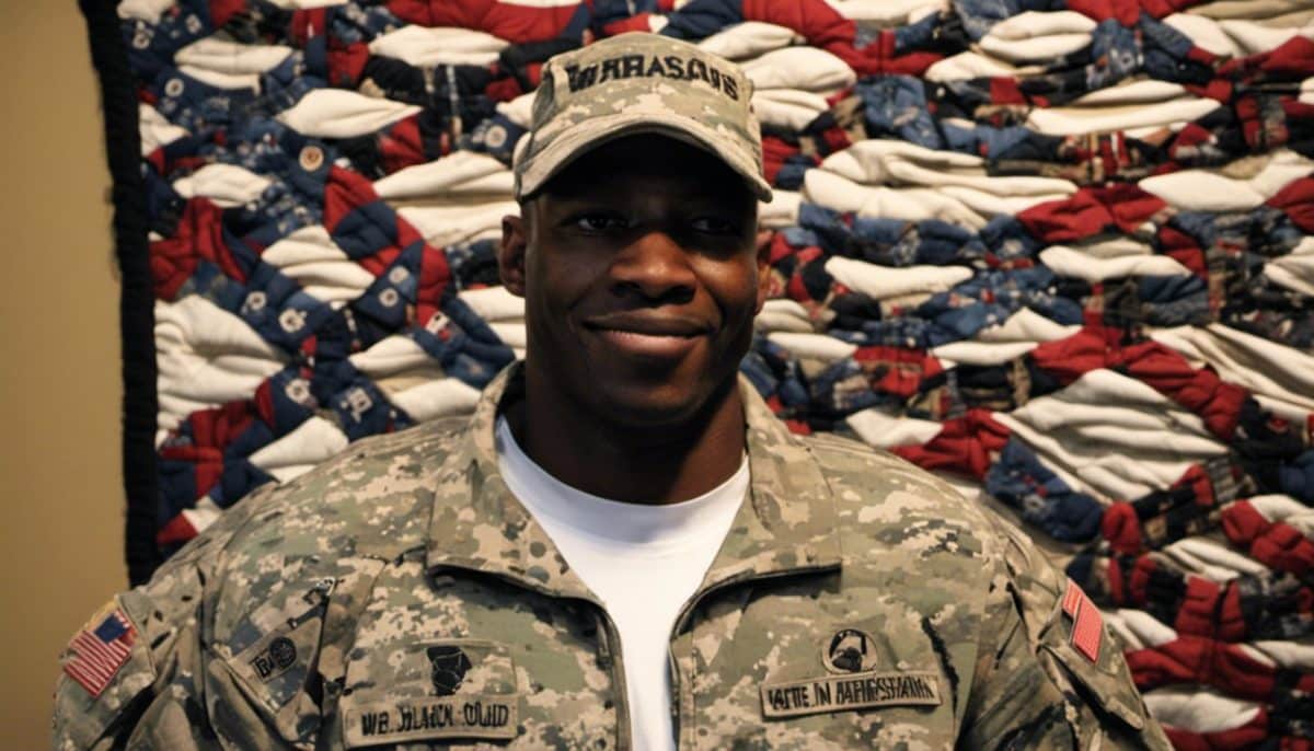 A soldier in uniform smiling in front of a quilt made from his military T shirts